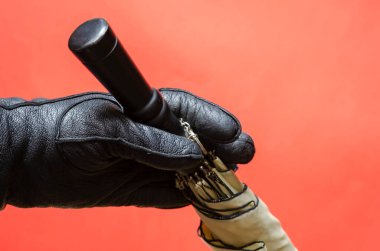 Siyah deri eldivenin içinde mercan zeminine karşı bir şemsiye var. Kara saplı yağmur ve rüzgar koruma aksesuarı. Bir açıyla üstteki görünüm.