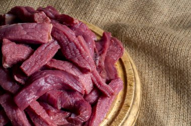 Tahta kesme tahtasındaki çiğ et şeritleri. Pişmemiş sığır stroganoff porsiyonu. Yemek pişirme ya da kasap dükkanı. Yan görüş. Seçici odak.