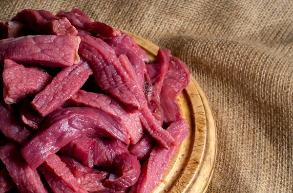 Tahta kesme tahtasındaki çiğ et şeritleri. Pişmemiş sığır stroganoff porsiyonu. Yemek pişirme ya da kasap dükkanı. Yan görüş. Seçici odak.