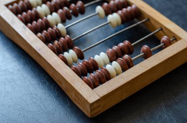 Siyah bir masada yakın plan ahşap bir abaküs. Matematiksel hesaplamalar için eski bir araç. Muhasebeciler, muhasebeciler, matematikçiler için çalışma aracı.