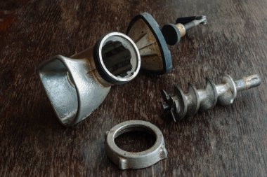 Tahta masada parçalanmış eski model kıyma makinesi. Kıyma makinesinden yapılmış demir gövde, özel bıçak ve fındık. Göz hizasında ateş ediliyor. Eski mutfak gereçleri.