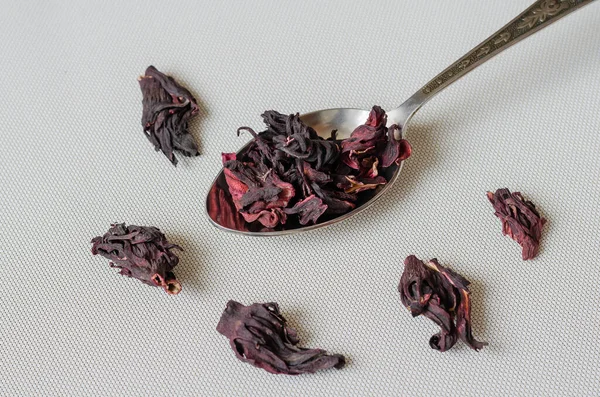 Metal spoon with dry hibiscus petals. Dehydrated Sudanese Rose or Hibiscus. Base for a hot or cold drink. Medicinal herbs. Selective focus.