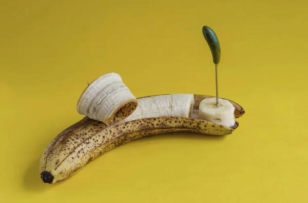 过熟的香蕉 有部分剥皮的皮和有壳的扭曲物 黄色背景下的甜果片 侧视图 有选择的重点 — 图库照片