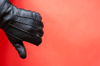 Mercan arka planında deri eldivenli bir erkek el hareketi. Adam elini siyah deri eldivenle gösteriyor. Yan görüş. Seçici odak.