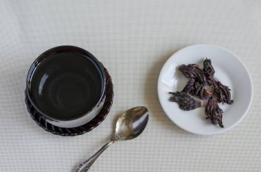 Kaynar suyla siyah cam bardak, metal kaşık ve kuru amber yaprağı. Susuz Sudan gülü, amberçiçeği çayı yapmak için. Şifalı bitkiler. Seçici odak.