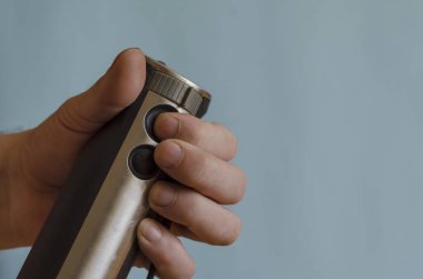 Elinizde bir mutfak mikseri ve bir hortum var. Bir adamın sol eli elektrikli mutfak helikopterinin güç düğmesine basar. Kafkasyalı, 43-45 yaşlarında. Mutfak aletleri..