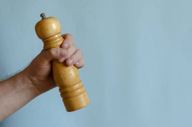Yetişkin adam elinde ahşap bir biber değirmeni tutuyor. Klasik baharat helikopteri. Avrupalı erkek, 43-45 yaşlarında. Mutfak aletleri