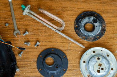 Parçalanmış su ısıtıcısının detayları. Anode, ısıtma elementi, sıcaklık sensörü, contalar, flanj. Su ısıtıcısının tamiri için yeterliydi. Ev aletlerinin tamiri için ticari hizmetler. Yukarıdan görüntüle.