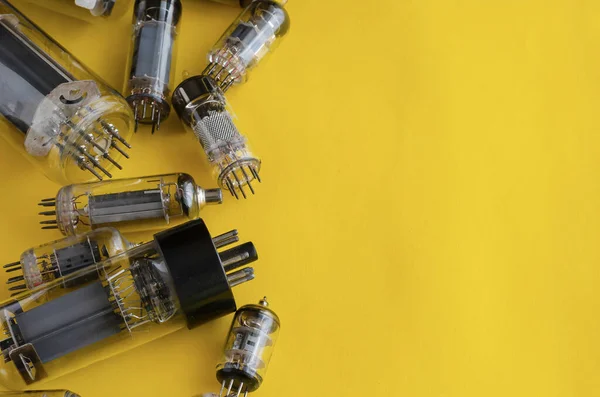 Random vacuum tubes on a yellow background. A group of radio tubes of different sizes and purposes. Copy space. Selective focus.