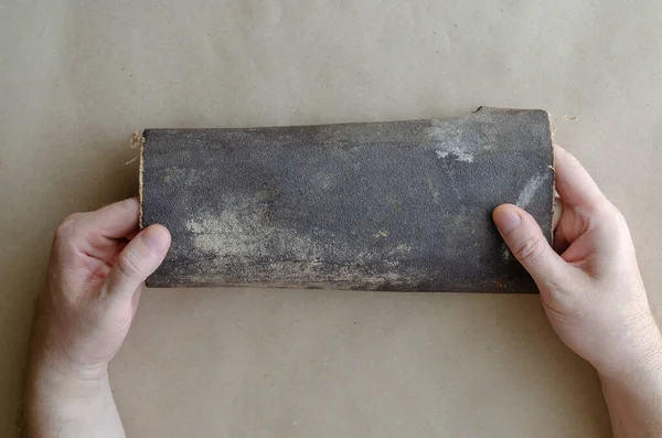 Beyaz bir adam elinde eski bir zımpara kağıdı tutuyor. Elinde zımpara kağıdı tomarı olan orta yaşlı bir adamın eli. El işçiliği. Seçici odak.