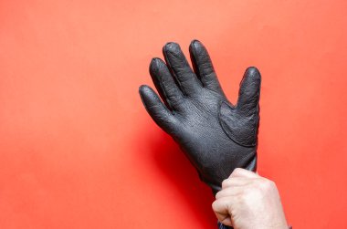 Adam eline siyah deri eldiven takıyor. Yetişkin bir erkek, beyaz, orta yaşlı. Yan görüş. Seçici odak.