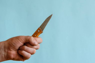 Erkek eli ahşap saplı küçük eski bir bıçak. Zorbanın sol elinde paslı keskin bir bıçak var. Avrupa ırkının orta yaşlı adamı..