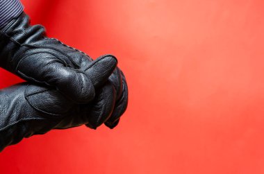 Mercan arka planında deri eldivenli bir erkek el hareketi. Adam elini siyah deri eldivenle gösteriyor. Yan görüş. Seçici odak.