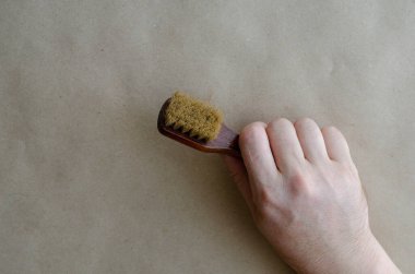 Bir adamın eli elbise için küçük bir fırça tutuyor. Ahşap fırçalı yetişkin bir adam. Kıyafetler için temizlik hizmetleri.