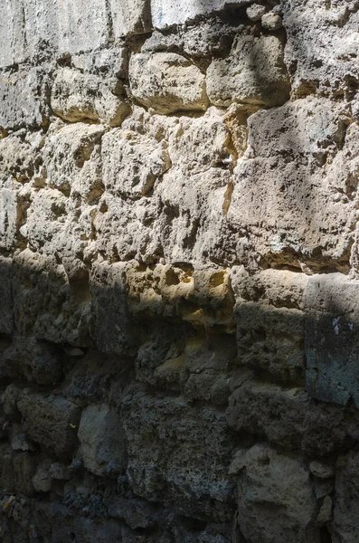 Old wall of limestone with grey seams, perspective view. Fragment of an old wall divided by sunlight and shadow. The concept of the struggle between good and evil.