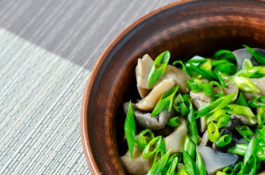 Mantar turşulu ve yeşil soğanlı şenlikli salata. Çeşitli orman mantarları, soğanlar ve sarımsaklı çamur kasesi. Organik yiyecekler. Servis seçeneği. Seçici odak.