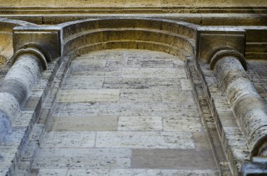Mermi kayasından yapılmış eski bir binanın ön cephesinin parçası. Dış duvarda iki sütun ve geri çekilen bir perspektif var. Turizm ve seyahat. Tepeden tırnağa. Seçici odak.