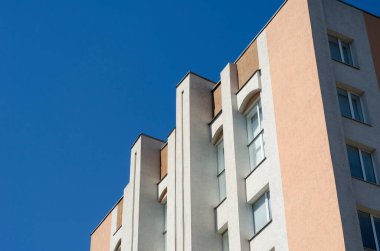 Mavi gökyüzüne karşı bir idari binanın parçası. Uzun pencereli gri ve kırmızı bir bina. Modern mimari. Şehir manzarası.