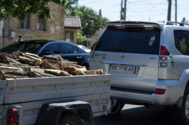 Nikolaev, Ukrayna, 17 Ağustos 2020: Toyota Prado yakacak odunlu bir römorku şehir caddesi boyunca çeker. Şehir trafiğinde yakacak odunu olan gri bir cip. Şehir hayatı.