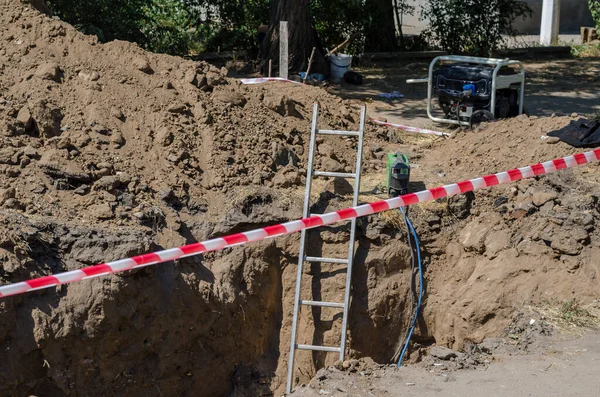 Kaynak makinesi, jeneratör ve merdiven kazılmış siperin yanında. Tamirat yeri engelleyici çitlerle çevrili. Güvenlik. Acil Boru Hattı Tamiri