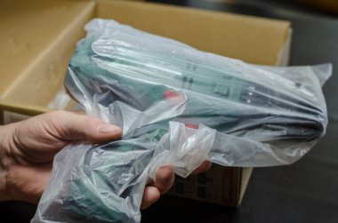 Erkek eller eşyalarınızı çıkarın ve elektrikli matkabı inceleyin. Yetişkin bir adam internetten satın alınmış elektrikli bir aleti inceliyor. Seçici odaklanma. Bir serinin parçası