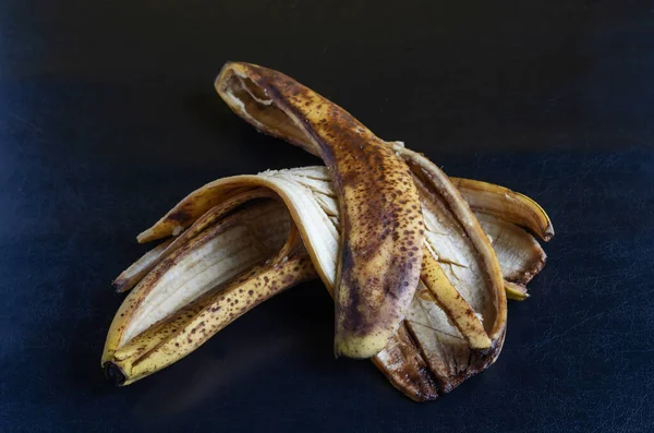 Detailed photo Discarded banana peel on black background. The peel of overripe bananas with brown spots. Food waste. Close-up. Selective focus.