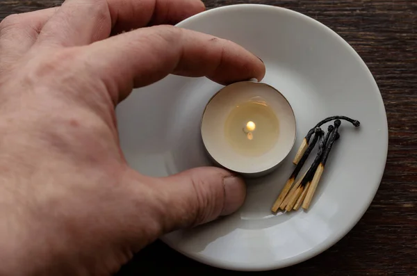 Male Hand Holds Small Burning Candle White Saucer Burnt Matches — Stock Photo, Image