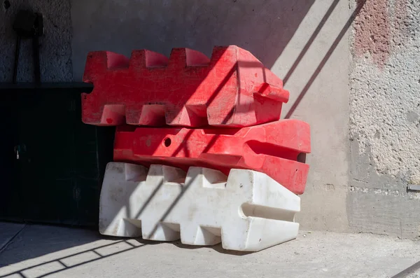 Duvara yığılmış yol suyu dolu plastik bariyerler. İki kırmızı ve bir beyaz yol güvenlik çiti. Güvenlik. Seçici odak.