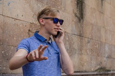 Güneş gözlüklü genç adamın portresi telefonda konuşuyor. Avrupai bir ırkın adamı telefon görüşmeleri sırasında dikkatini dağıtmamasını ister. Yaşam biçimi.