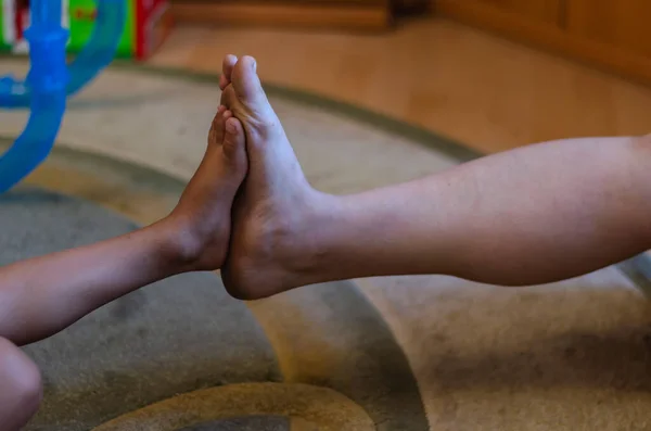 Touching the feet of an adult woman and a preschool boy. The child and the mother compare the size of the legs resting on the feet. Happy life. Selective focus.