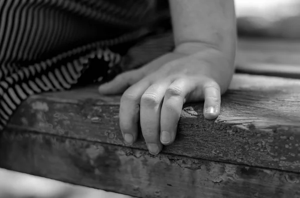 Close-up of a female hand on a park bench. An adult woman sits alone on a park bench. Love and relationship concept. Selective focus.