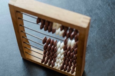 Siyah bir masada yakın plan ahşap bir abaküs. Matematiksel hesaplamalar için eski bir araç. Muhasebeciler, muhasebeciler, matematikçiler için çalışma aracı.