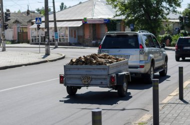 Nikolaev, Ukrayna, 20 Ağustos 2020: Toyota Prado yakacak odunlu bir römorku şehir caddesi boyunca çeker. Şehir trafiğinde yakacak odunu olan gri bir cip. Şehir hayatı.
