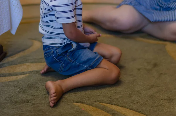 A mixed race boy sits on the floor indoors. Preschool child on the carpet. Happy life. Selective focus.