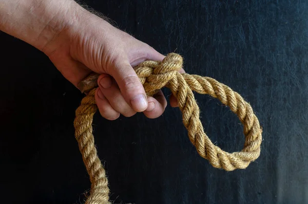 一个人的手在黑暗的背景上握着一根结的绳子 一个手里拿着粗绳的成熟男人 积极的生活方式 有选择的重点 — 图库照片