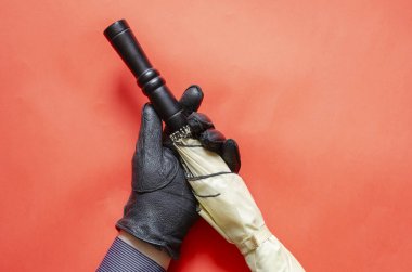 Siyah deri eldivenin içinde mercan zeminine karşı bir şemsiye var. Kara saplı yağmur ve rüzgar koruma aksesuarı. Bir açıyla üstteki görünüm.