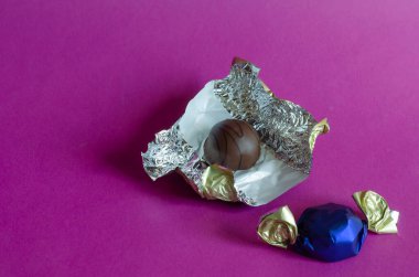 Pembe arka planda iki çikolata şekeri. Paketli ya da ambalajsız şekerlemeler. Tatlı ikramlar. Uzayı kopyala Seçici odak.