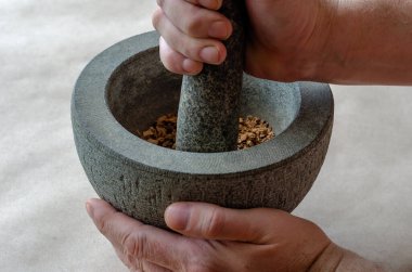 El, taş havanda kurutulmuş şifalı bitkilerin kökünü öğütüyor. Beyaz, orta yaşlı bir adam. Alternatif tıp. Şifalı bitkiler..