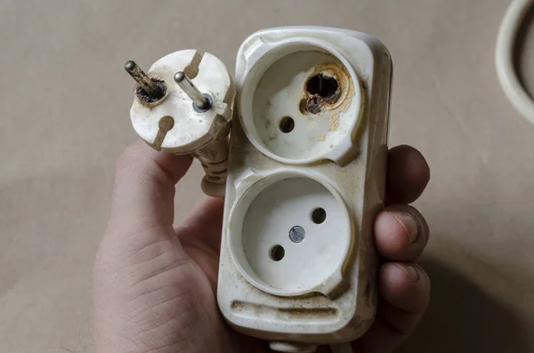 一位电工演示了一个电源插座被烧毁的情景 白色延长线后短路在男性手中 电气安全 — 图库照片
