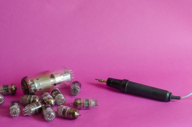 Rastgele radyo tüpleri ve pembe arka planda indüksiyon demiri grubu. Eski radyo parçaları. Toplama ya da geri dönüşüm. Seçici odak.