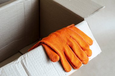 Koruyucu eldivenler boş bir karton kutuda yatıyor. Paketleme için karton kutuyu aç. Paketlerin teslimatı ve paketlenmesi için hizmetler. Seçici odak.