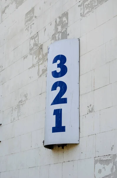 Semicircular sign on the wall with numbers 3,2,1. Vertical signboard on a peeling brick wall. Selective focus.