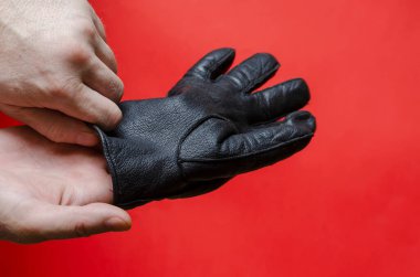 Adam eline siyah deri eldiven takıyor. Yetişkin bir erkek, beyaz, orta yaşlı. Yan görüş. Seçici odak.