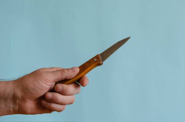 Erkek eli ahşap saplı küçük eski bir bıçak. Zorbanın sol elinde paslı keskin bir bıçak var. Avrupa ırkının orta yaşlı adamı..