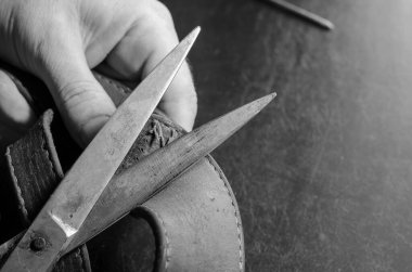 Elinde makas olan bir adam deri bir yakanın eski ipliklerini kesiyor. Metal makasla yetişkin bir adamın elleri. Evcil hayvan malzemeleri tamiri. Seçici odak.