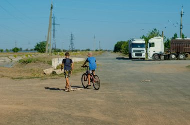 Nikolaev, Ukrayna - 15 Eylül 2020: İki çocuk toprak yolda tutkulu bir konuşma yaptı. Biri bisiklette, diğeri yaya olarak. Neşeli bir çocukluk. Arkadan bak..