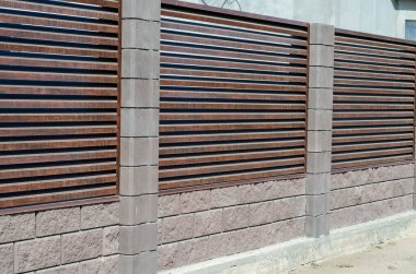 Gri taş kolonları olan kör çitler. Kulübenin etrafında kahverengi bir çit var. Özel mülk. Köy köyü.