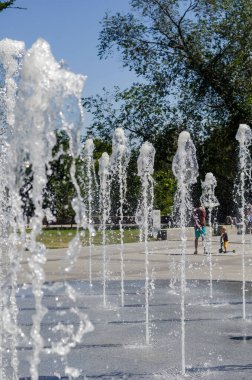 Nikolaev, Ukrayna - 17 Ağustos 2020: Kent meydanındaki şehir çeşmesinin serin akarsularının yanında gezinen sakinler. Yerden fışkıran serin ve berrak su fışkırıyor..