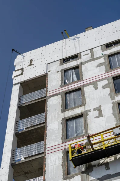 Thermal insulation of the walls of a new unfinished apartment building. Facade works on heat and moisture insulation of the outer walls of the building. Energy saving concept.