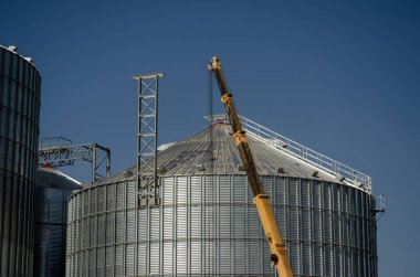 Limanda modern bir tahıl terminali inşa ediliyor. Mobil vinç patlaması silindirik bir metal silonun arka planında. Tahıl ihracatı.